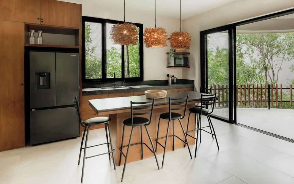 Second kitchen with dark countertops, premium appliances, bar seating, and terrace access.