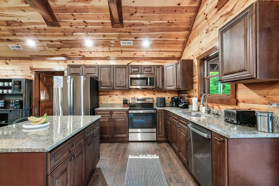 spacious kitchen with granite countertops and stainless steel appliances in a rustic cabin setting