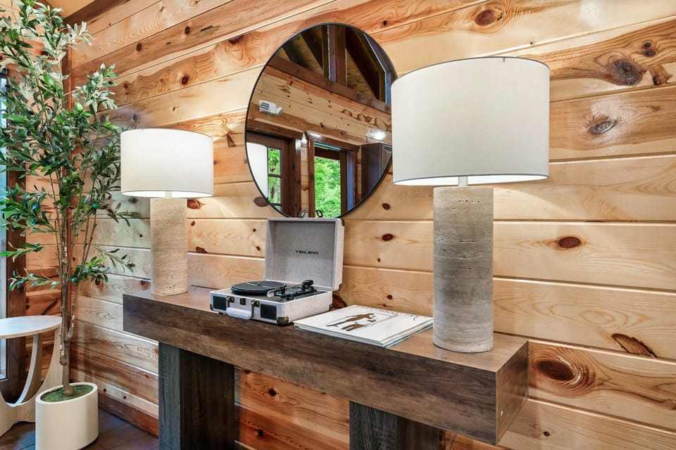 rustic wooden console table with twin lamps and a record player under a round mirror