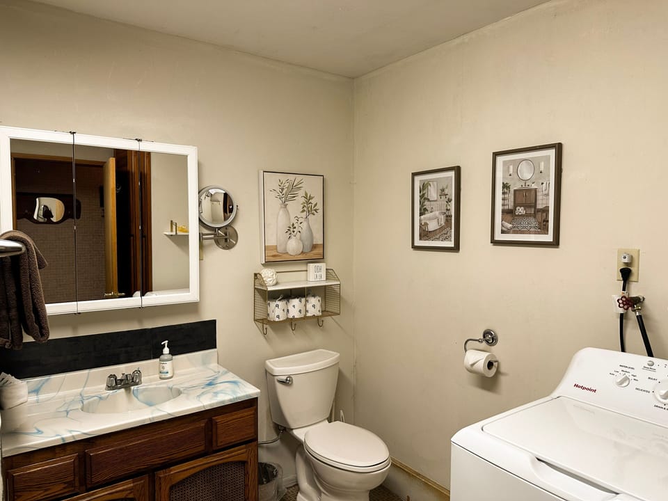 Bathroom featuring a wood vanity, white toilet, and in-room washing machine.