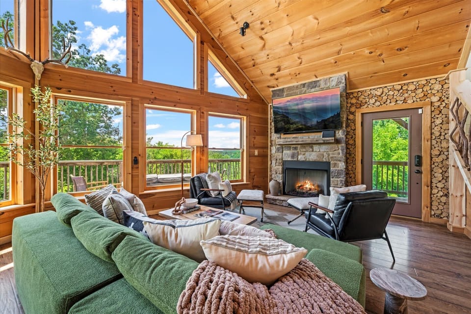 Our living room features expansive windows that flood the space with natural light and breathtaking views—paired with plush seating, a warm fireplace, and a Smart TV for the perfect mix of nature and comfort. 