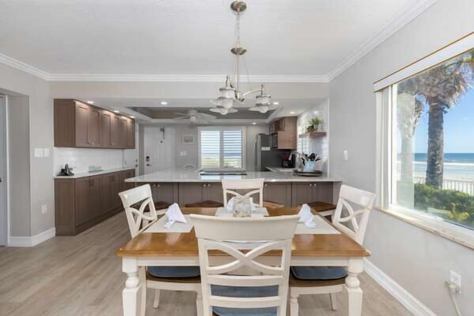 Dine with stunning ocean views in this bright coastal space featuring a modern kitchen, spacious dining area, and large windows showcasing the beach just steps away.