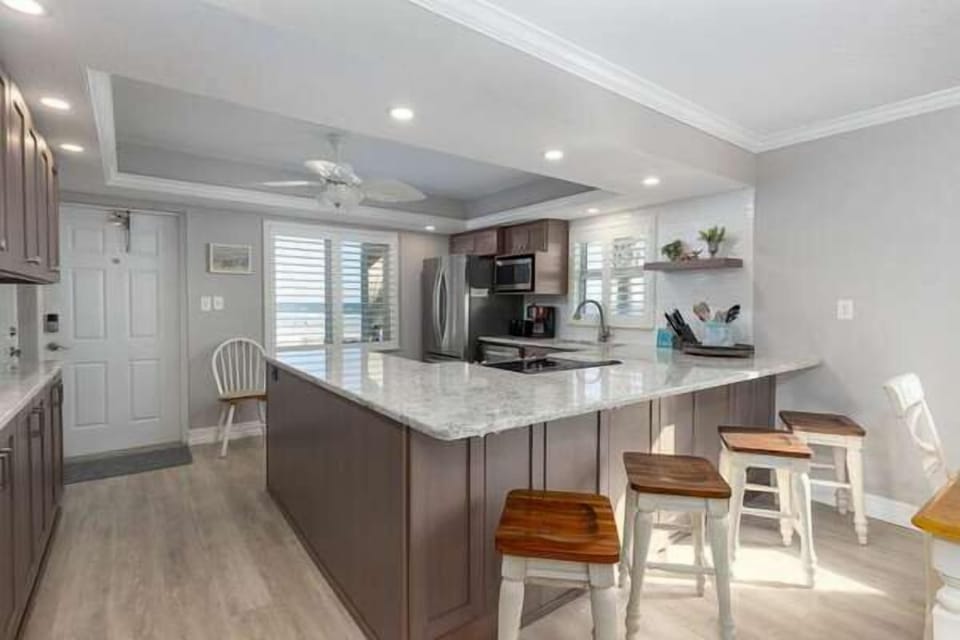 Cook with a view in this fully equipped beachside kitchen featuring stainless steel appliances, granite countertops, and a spacious breakfast bar with seating.