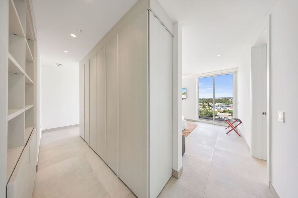 Step into your bright, modern hallway with sleek built-in storage. Ahead, your private space awaits with sweeping views framed by floor-to-ceiling windows.