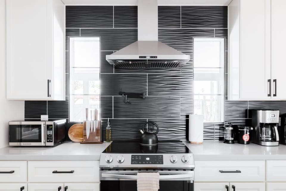 Sleek chef’s kitchen w/ pot filler, coffee station & bold tile