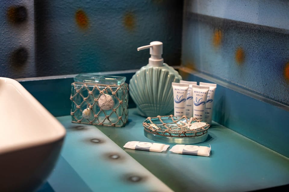 Coastal-themed bathroom amenities arranged on a turquoise countertop.