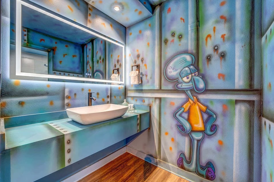 Bathroom with a custom cartoon-themed wall mural and modern illuminated mirror.