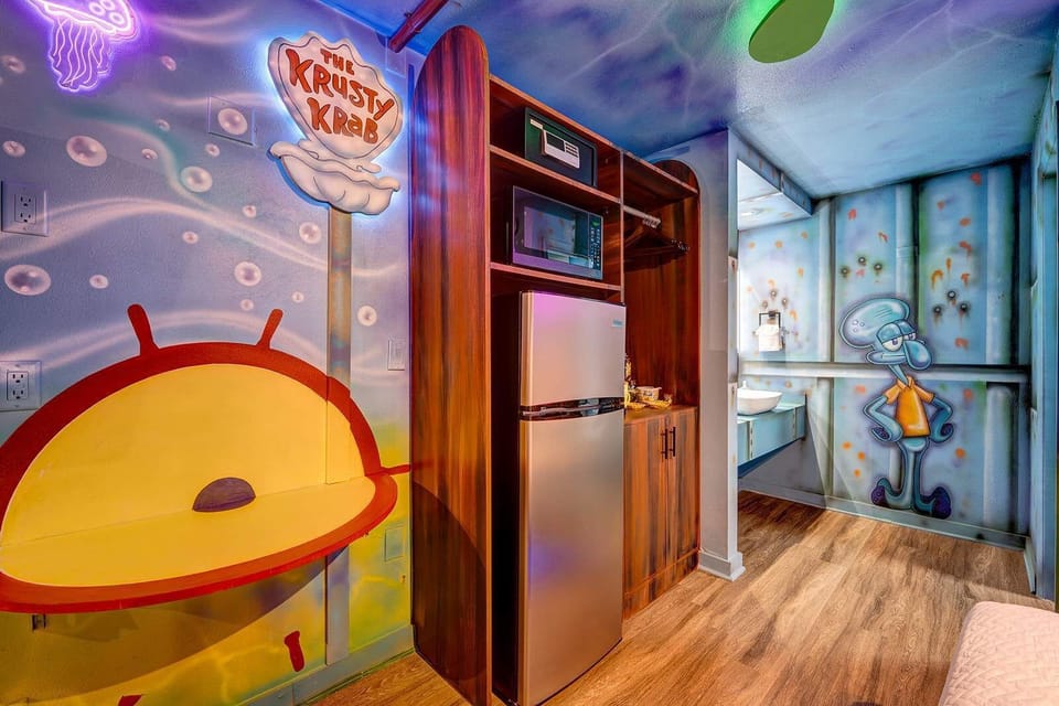 Kitchenette area with a mini fridge, microwave, and themed wall art inspired by the krusty krab and squidward.