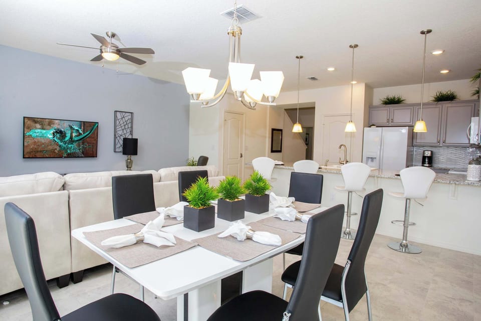 Open-concept dining zone: sleek white table, dark chairs, and a chic pendant light-modern, airy vibes for family meals.