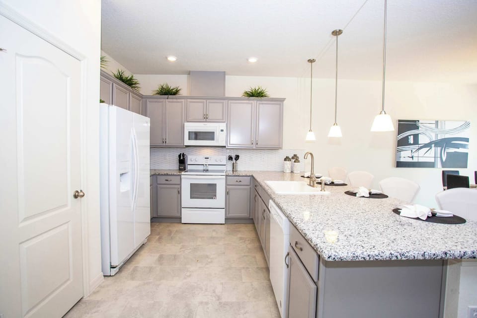Modern open-concept kitchen with gray cabinets, granite island, and stainless appliances-a bright, stylish hub for cooking and conversation.