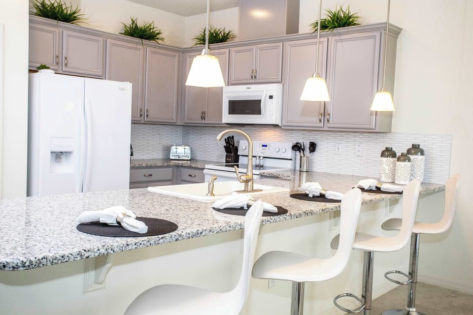 Bright, contemporary kitchen with a roomy island, pendant lighting, and chic breakfast-bar seating-space to cook, chat, and entertain.