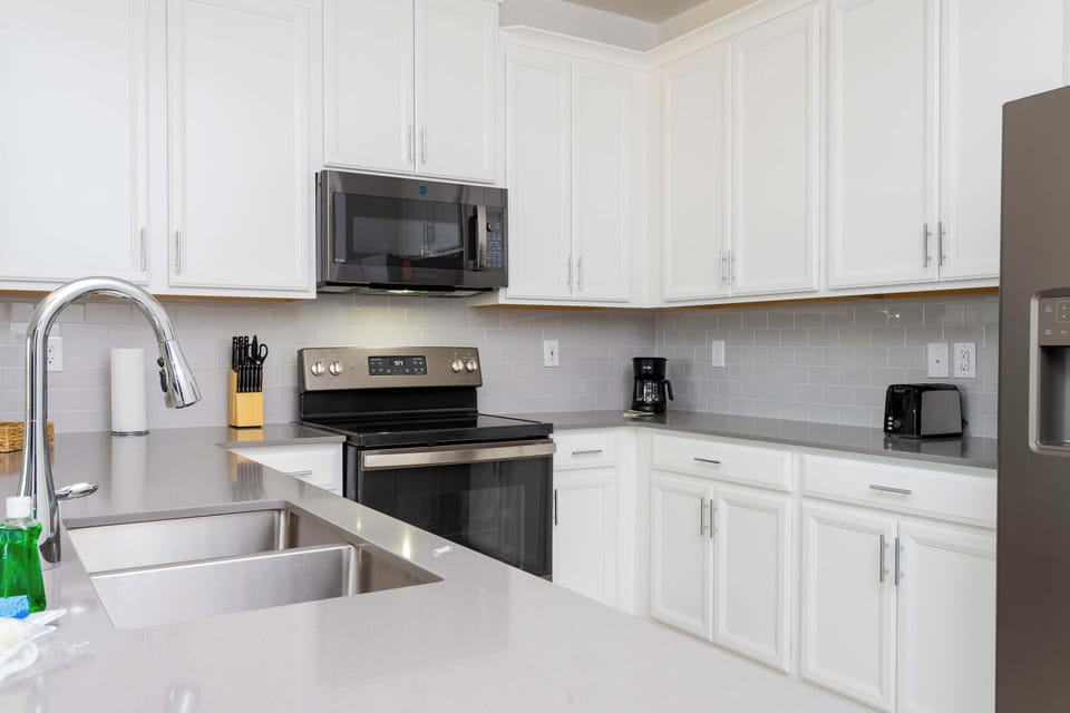 Cook up family favorites in this sleek, modern kitchen! Featuring crisp white cabinetry, stainless steel appliances, and plenty of counter space for meal prep after a day at the parks.