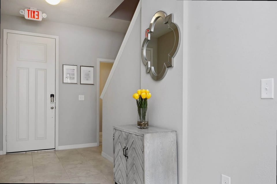 Step into a bright, welcoming foyer with a stylish chevron console, gleaming mirror, and fresh tulips—your inviting home-away-from-home arrival space.