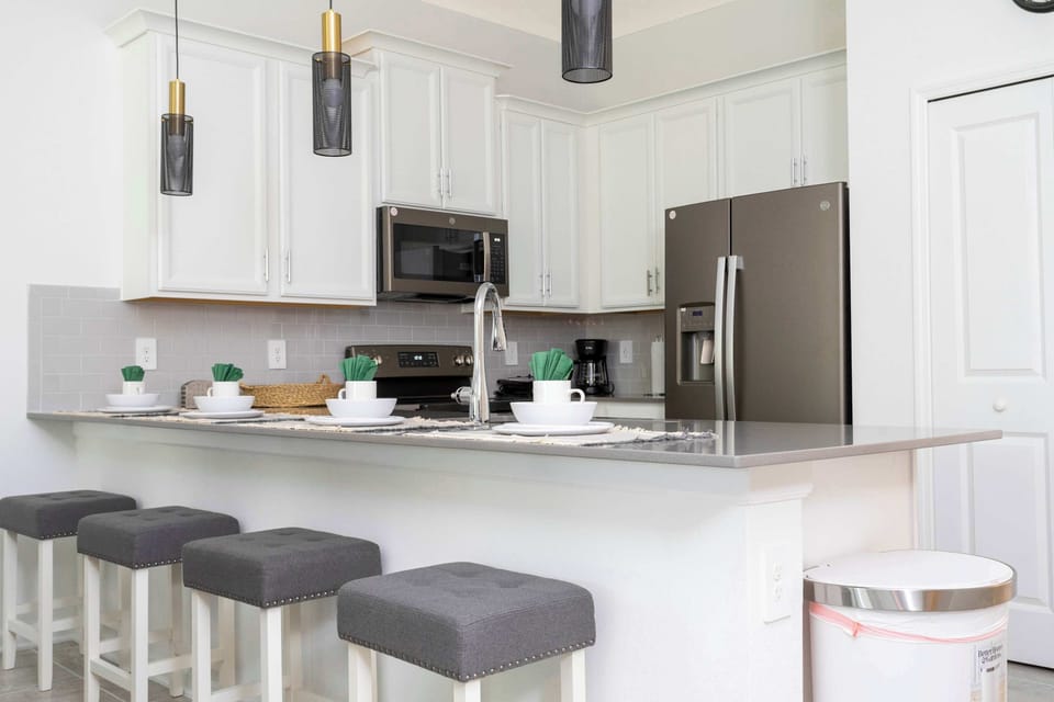 Bright kitchen with quartz island, seating for four at the breakfast bar, and modern pendant lights. Set for casual bites and conversation.