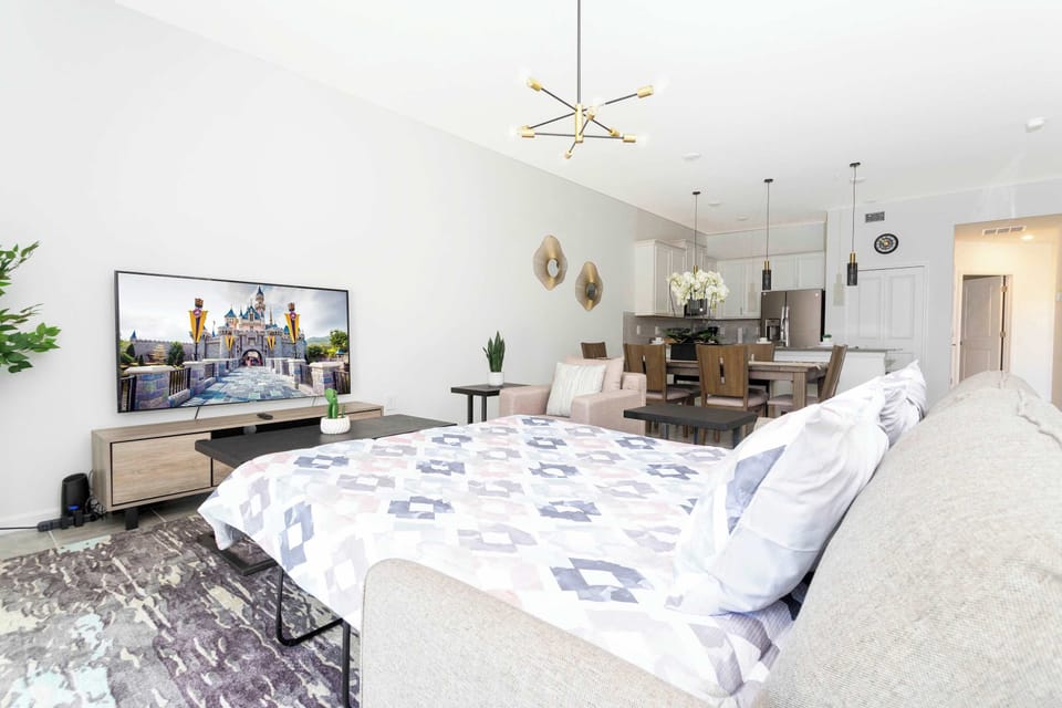 Bright lounge with big-screen TV and sleek pendant lighting, opening to a stylish kitchen and dining area. The sofa converts to a queen-size bed-perfect for movie nights.