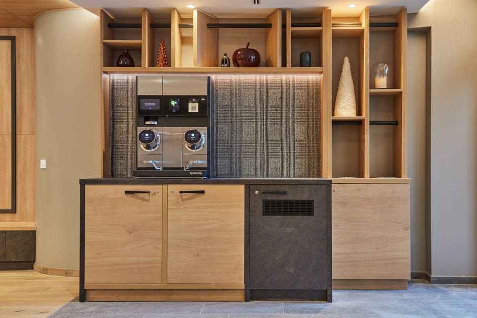 Coffee station with a Nespresso machine, light wood cabinetry, and open shelving — a convenient stop before hitting the slopes.