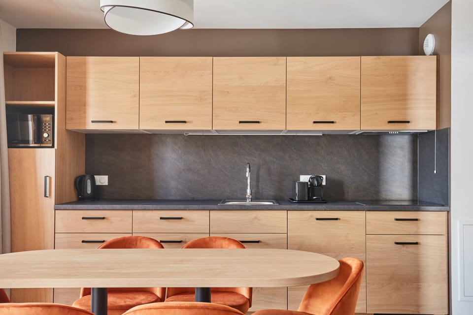 Kitchenette close-up with light cabinets, microwave, kettle, and a dark countertop — stovetop and dishwasher also included.