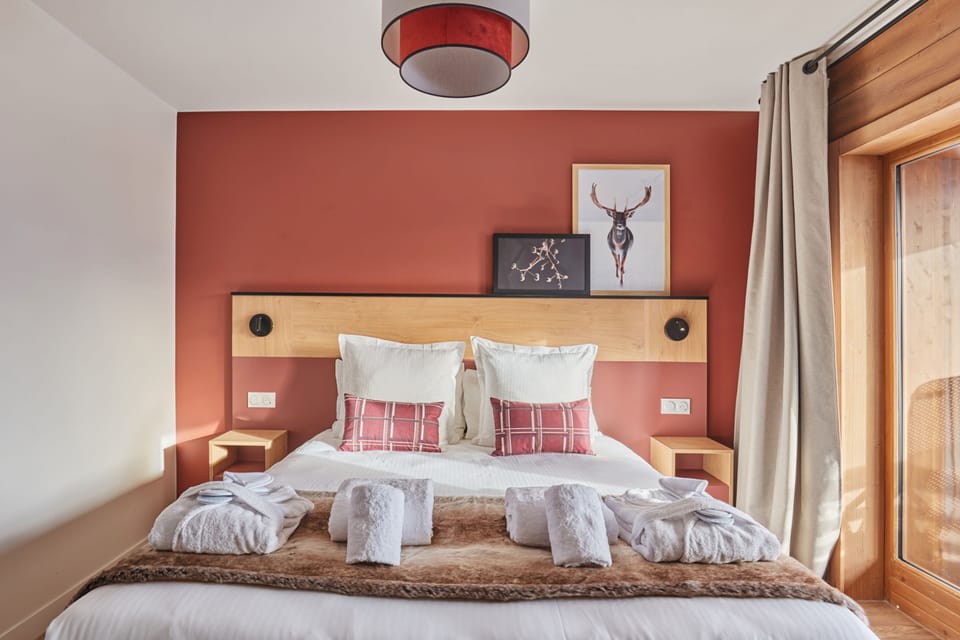 Natural light fills the bedroom through the balcony window — step outside for fresh alpine air after a day on the slopes.
