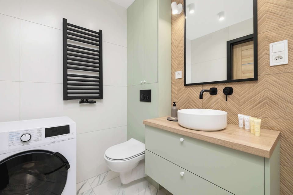 A bathroom vanity with twin sinks, a large mirror, and storage drawers in mint green.

