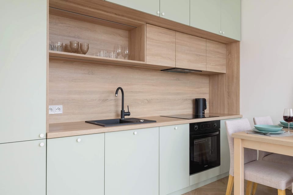 A kitchenette with wooden shelves, minimalist cabinetry, and a built-in coffee machine.

