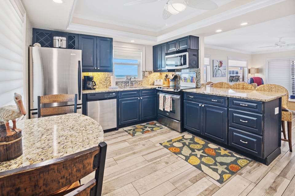 Cook in style with this modern beachside kitchen featuring granite countertops, stainless steel appliances, and ocean views. Perfect for preparing meals during your relaxing seaside getaway.