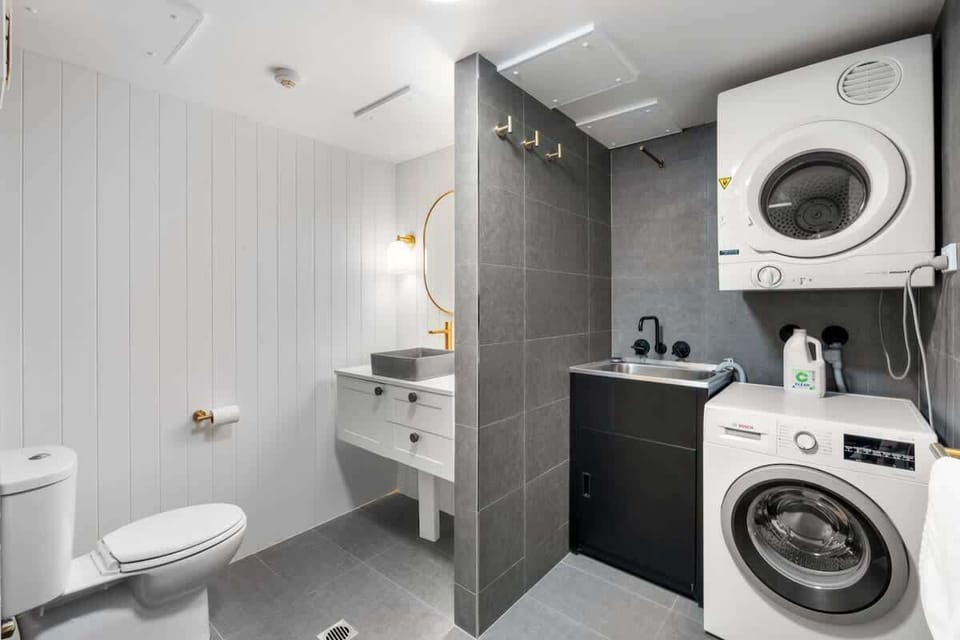 Spacious layout with toilet, stone-top vanity, and built-in laundry with washer and dryer.