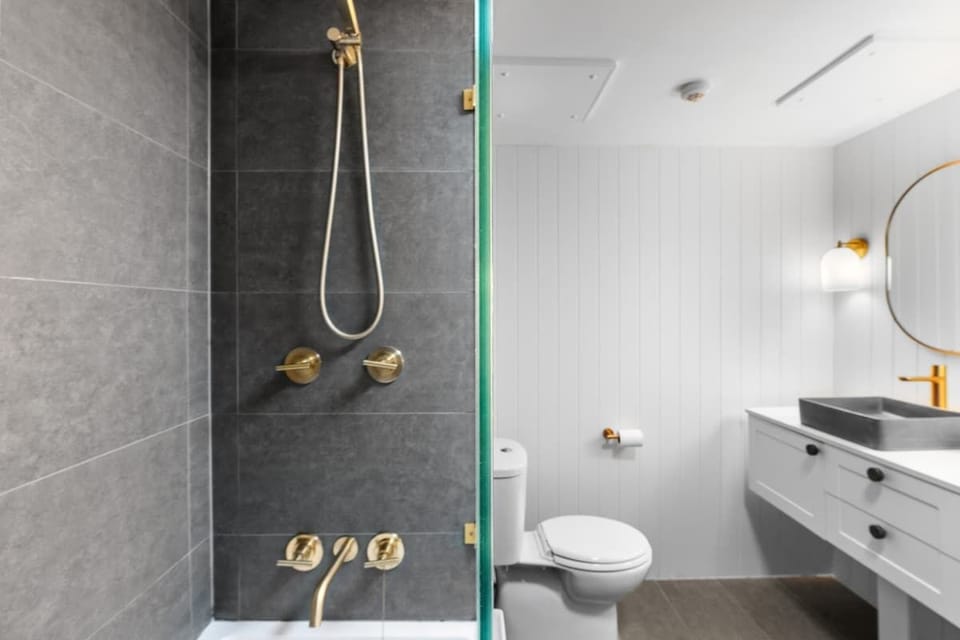 Renovated bathroom featuring gold tapware and a stylish walk-in shower for a touch of luxury.