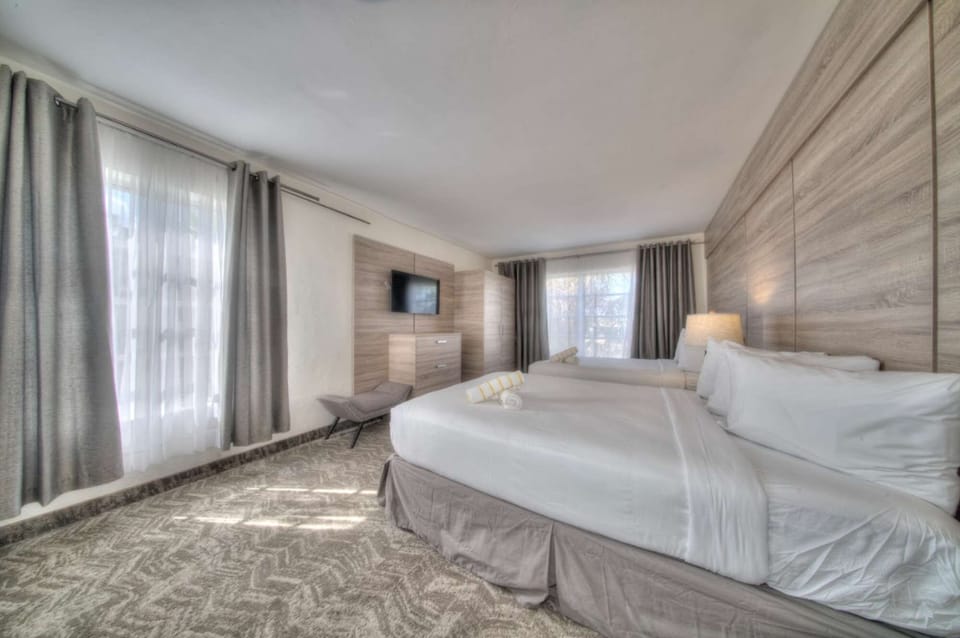Bedroom with beds, curtains, carpet flooring, and side table