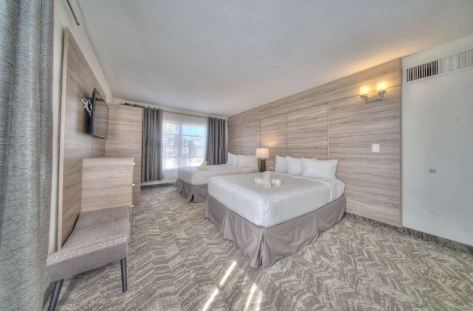 Bedroom view with two bed, dresser, windows, and wall lighting