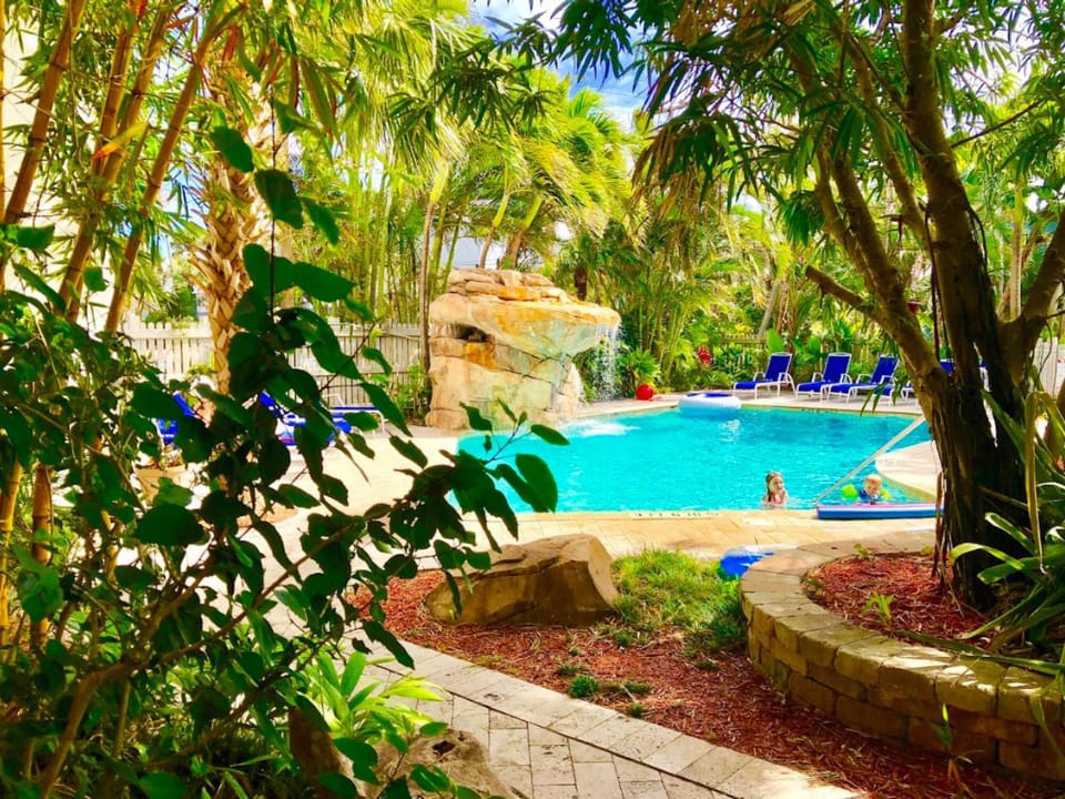 Pathway through trees with view of pool and surrounding greenery