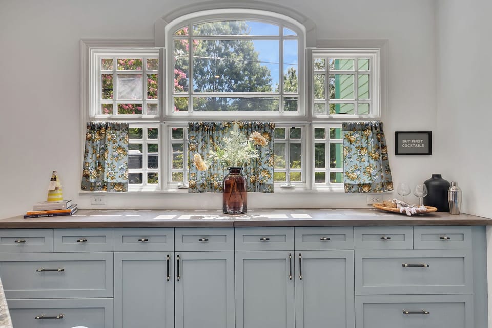 A  charming kitchen or bar area featuring light gray-blue cabinetry