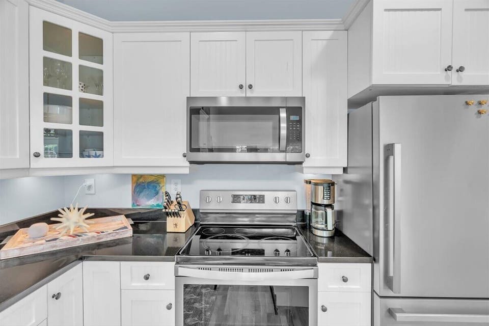 Your fully equipped kitchen features sleek white cabinets, granite counters, and stainless appliances for effortless meal prep during your stay.