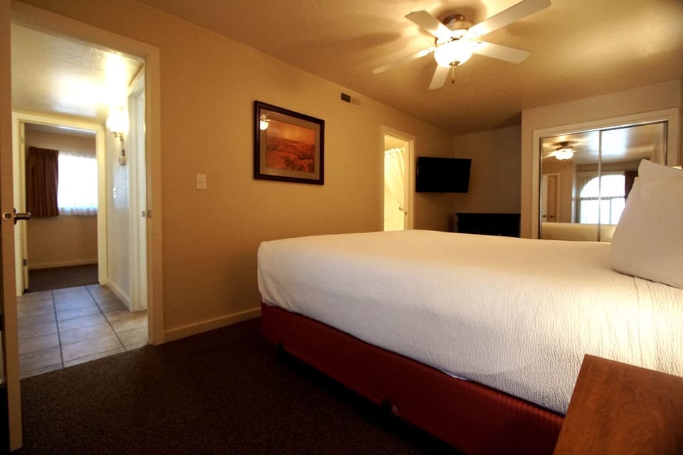 Queen bed in the second bedroom with reading lamp and warm neutral tones