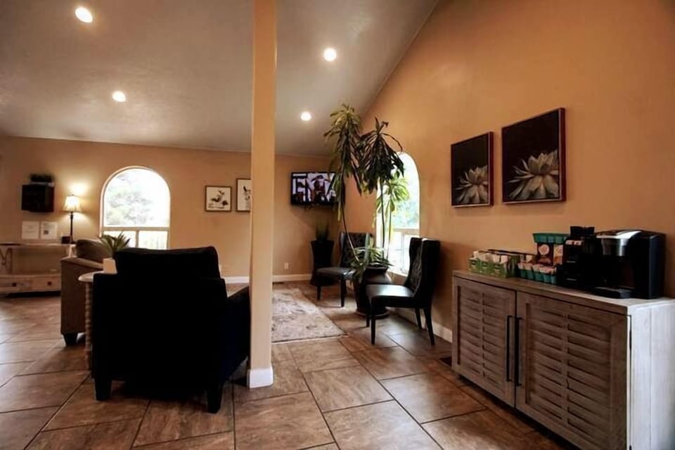 Lobby lounge with vaulted ceiling, wall-mounted TV, and a coffee station stocked with pods and a Keurig