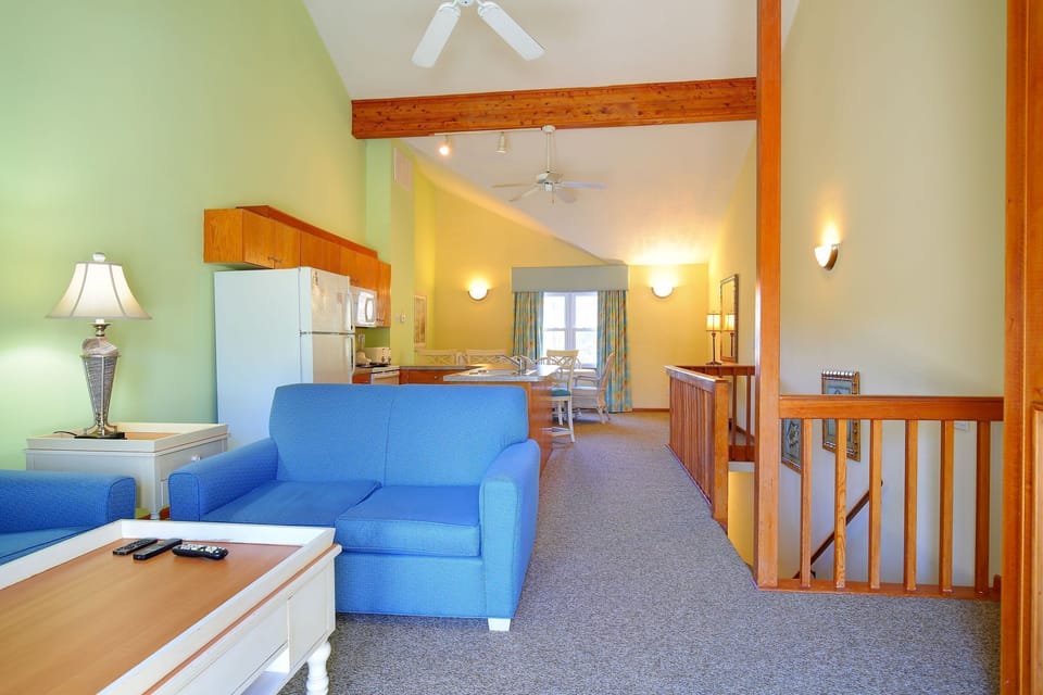 The spacious living area features vibrant green walls and a cozy blue sofa, perfect for relaxing after a day at the beach.