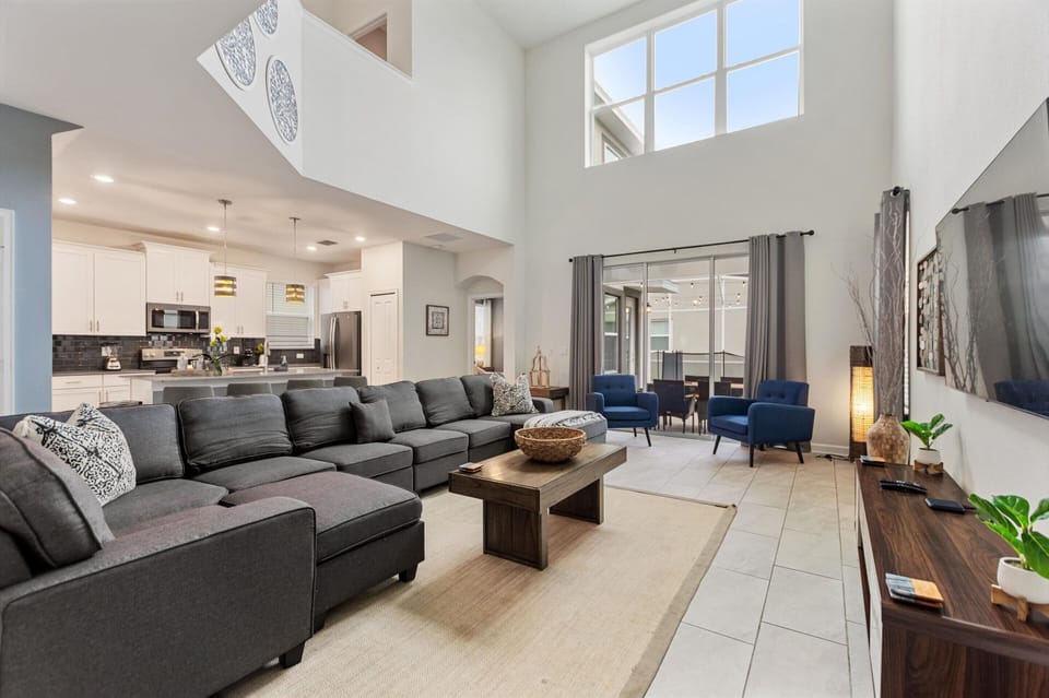 Living Room Area with TV, Pool Access & Kitchen in Back Ground