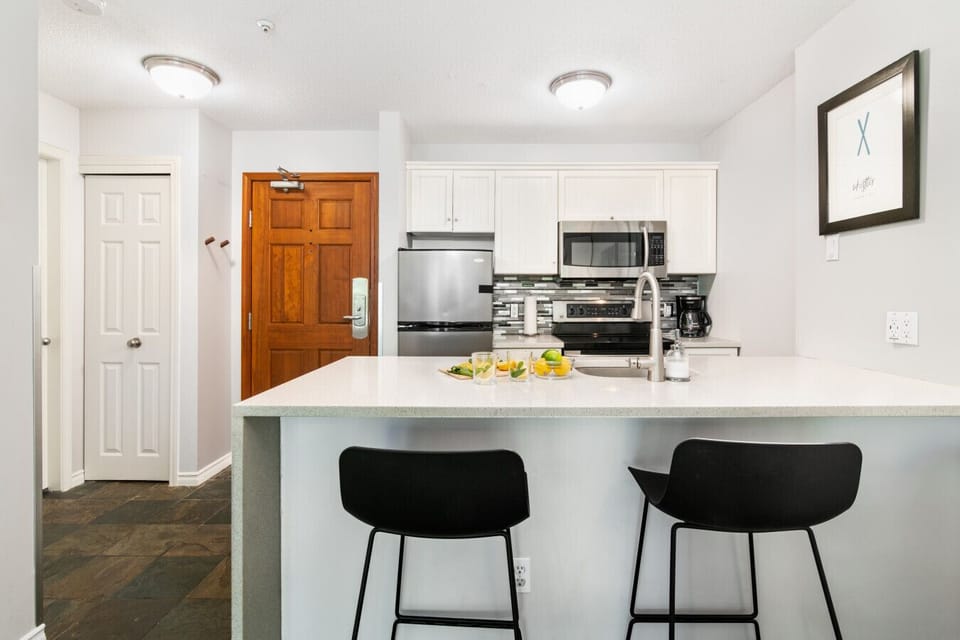 Modern kitchen with island and two bar stools, fully equipped for easy meals