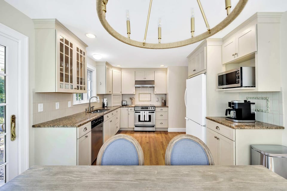 Bright and fully equipped kitchen with granite countertops, stainless steel stove, and built-in microwave.