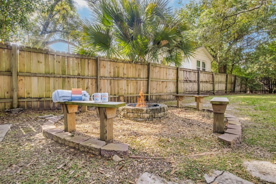 Fully fenced private backyard with fire pit provides space for family gatherings and evening relaxation in downtown Pensacola.
