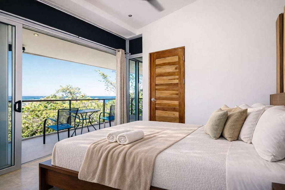 Bright Ocean-View Bedroom with Private Balcony Access, Sliding Glass Doors & Peaceful Tropical Surroundings for a Relaxing Stay
