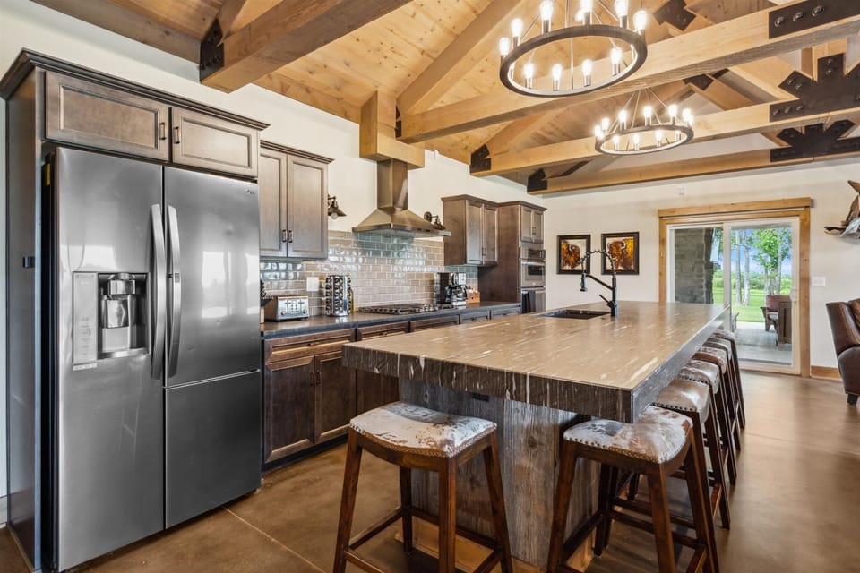 Spacious chef’s kitchen with a massive granite island, stainless steel appliances, and rustic finishes designed for gathering and entertaining.
