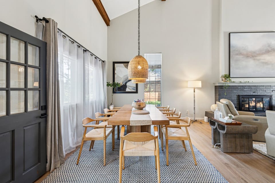 Gather around the expansive dining table under warm pendant lighting in this elegant open-concept space. With seating for ten, natural light, and a cozy view of the fireplace, it’s perfect for group meals, celebrations, or quiet mornings with coffee.