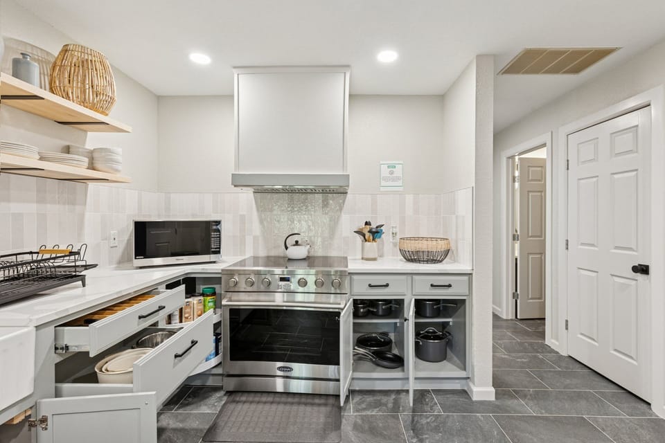 Cook like a pro with this high-end oven and gas range, tucked beneath a custom range hood and tile backsplash.