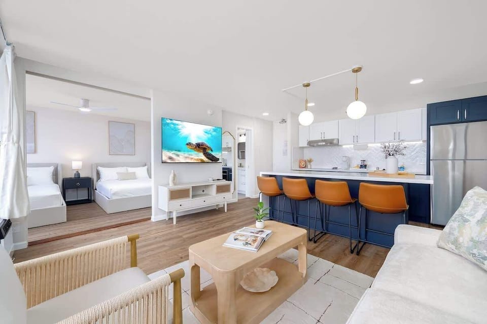 This modern open-concept living space seamlessly connects a cozy living area with a fully equipped kitchen and dining area, perfect for relaxed living and entertaining.