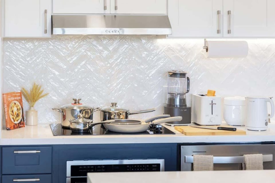 Whip up your favorite meals in this well-appointed kitchen, featuring some pots and pans, modern appliances, and a stylish chevron-patterned backsplash.