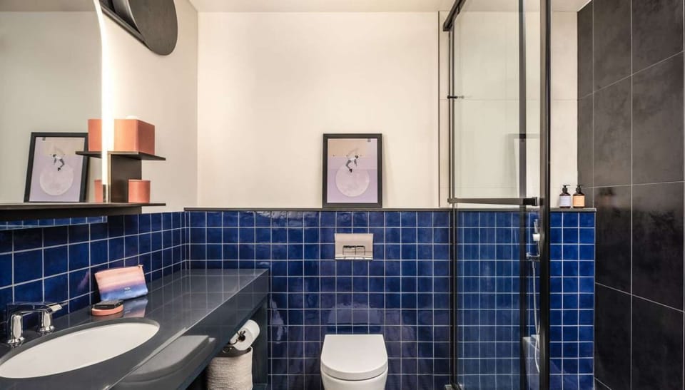 Bathroom with blue tile walls, walk-in shower, and wall art