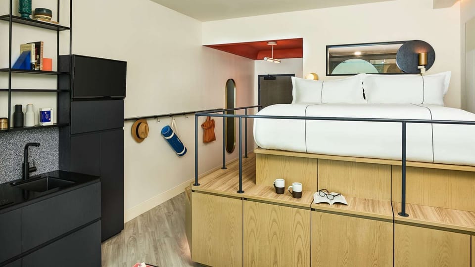Lofted bed with deep drawers, yoga mat, and black kitchen setup