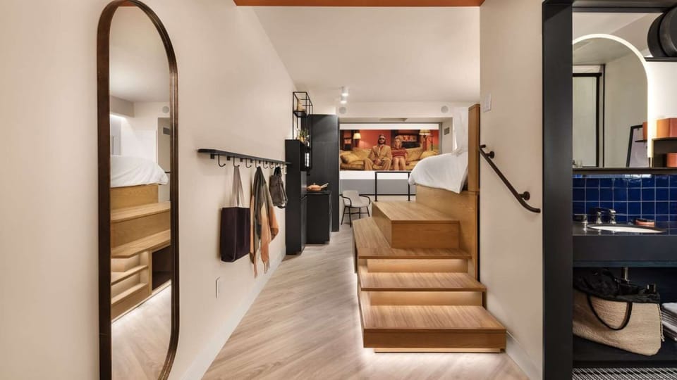View from entry shows lofted bed, mirror, kitchen, and bathroom
