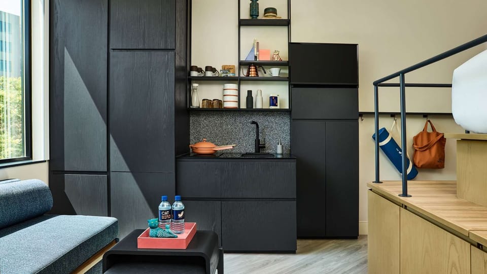 Compact kitchen beside steps to bed with open shelves and gear