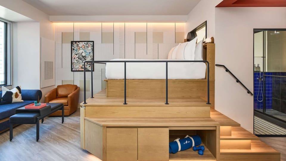 Room with lofted bed, sofa, storage, and walk-in shower nearby